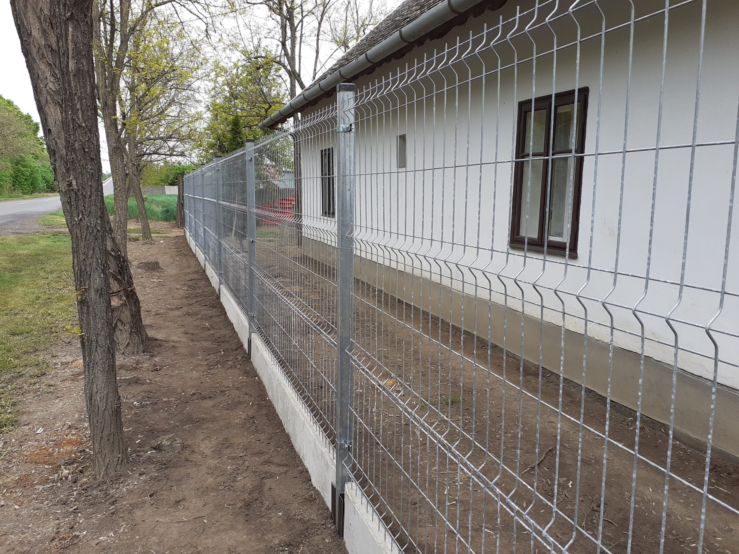 Régi ház frontján 3d táblás kerítés húzódik végig beton alappal