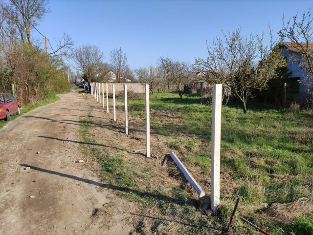 Világos betonoszlopok jelölik egy sarki telek határát.