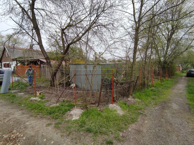 Sarki telek lebontott kerítéssel piros fém oszlopokkal